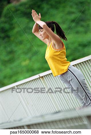Woman standing on bridge with hands together over head View Large Photo Image Stock Photo - Woman standing on bridge with hands together over head. Fotosearch