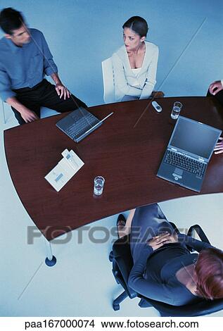 Business people around desk, elevated view View Large Photo Image Picture - Business people around desk, elevated view. Fotosearch