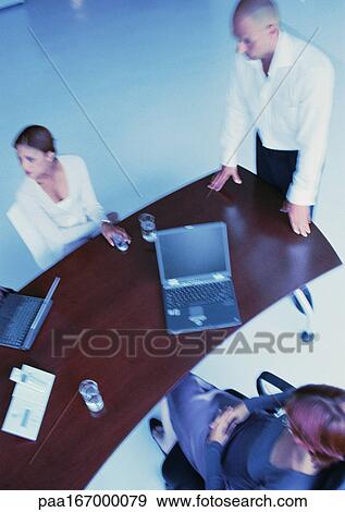 Business people around desk, elevated view View Large Photo Image Stock Photo - Business people around desk, elevated view. Fotosearch