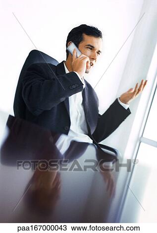 Businessman at desk using phone View Large Photo Image Stock Image - Businessman at desk using phone. Fotosearch