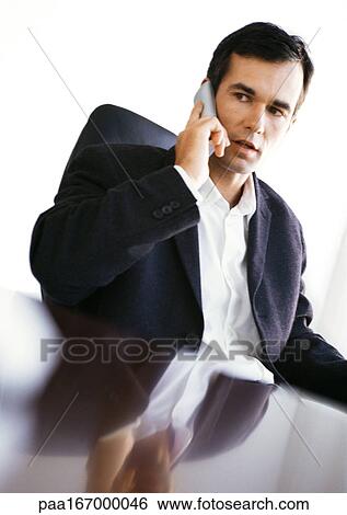 Businessman at desk using phone View Large Photo Image Stock Photograph - Businessman at desk using phone. Fotosearch