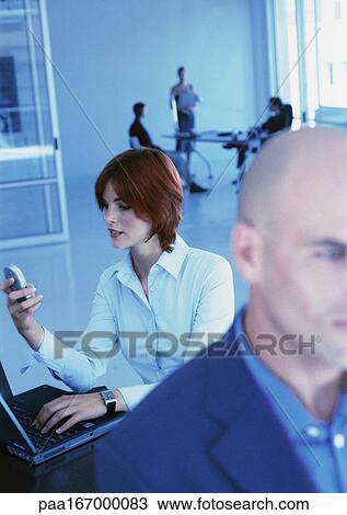 Businesspeople in office, woman using cell phone View Large Photo Image Stock Image - Businesspeople in office, woman using cell phone. Fotosearch