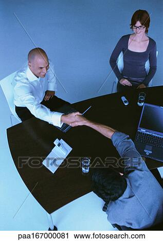 Businesspeople sitting at desk, two men shaking hands, elevated view View Large Photo Image Stock Image - Businesspeople sitting at desk, two men shaking hands, elevated view. Fotosearch