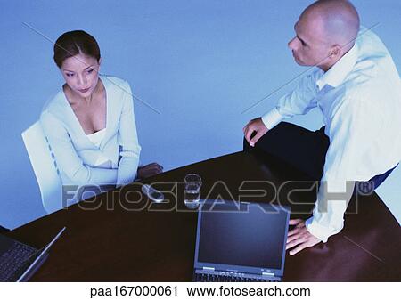 Businesswoman in chair, man sitting on desk, elevated view View Large Photo Image Stock Image - Businesswoman in chair, man sitting on desk, elevated view. Fotosearch