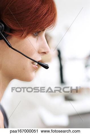 Stock Image - Woman wearing headset, side view. Fotosearch