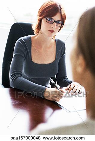 Women at desk, one holding pen View Large Photo Image Stock Photo - Women at desk, one holding pen. Fotosearch