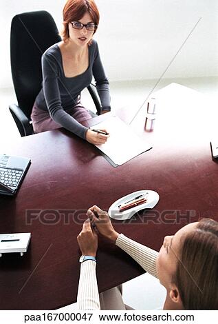 Women sitting at desk View Large Photo Image Stock Photo - Women sitting at desk. Fotosearch