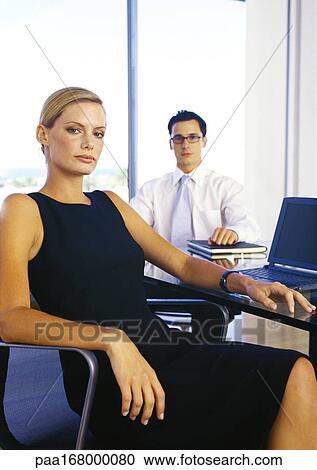 Businessman and woman sitting in office, portrait View Large Photo Image Stock Image - Businessman and woman sitting in office, portrait. Fotosearch