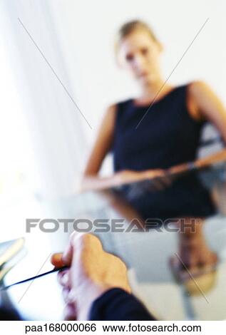 Businesswoman sitting at table, man's hand in foreground View Large Photo Image Stock Photograph - Businesswoman sitting at table, man's hand in foreground. Fotosearch