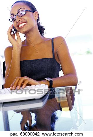 Businesswoman using cell phone and computer View Large Photo Image Stock Image - Businesswoman using cell phone and computer. Fotosearch