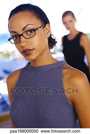 Businesswoman wearing glasses, second woman blurred in background, portrait View Large Photo Image Stock Image - Businesswoman wearing glasses, second woman blurred in background, portrait. Fotosearch