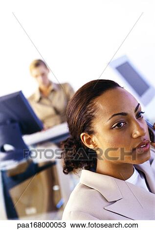 Businesswomen in office, one using cell phone, second using computer View Large Photo Image Stock Image - Businesswomen in office, one using cell phone, second using computer. Fotosearch
