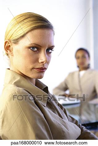 Stock Image - Two women, one looking into camera, portrait. Fotosearch