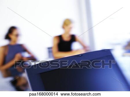 Women sitting at desk, blurred View Large Photo Image Picture - Women sitting at desk, blurred. Fotosearch