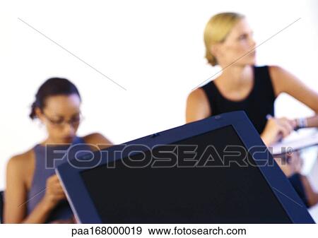 Women sitting at desk, blurred View Large Photo Image Stock Photo - Women sitting at desk, blurred. Fotosearch