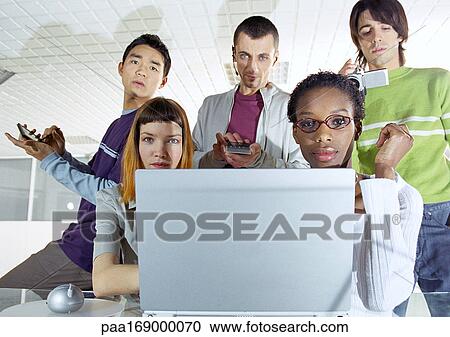 Group of young people gathered around computer View Large Photo Image Stock Image - Group of young people gathered around computer. Fotosearch