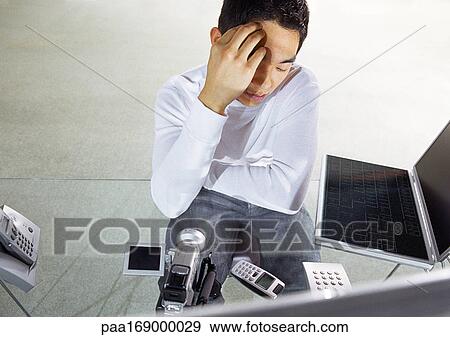 Man at desk looking at high technology devices View Large Photo Image Stock Photo - Man at desk looking at high technology devices. Fotosearch