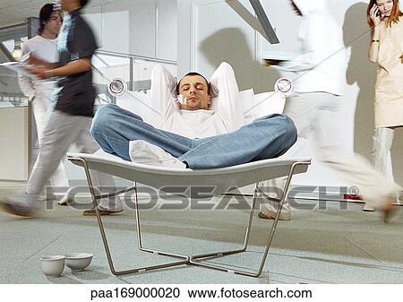 Man in office sleeping in chair while people work View Large Photo Image Stock Image - Man in office sleeping in chair while people work. Fotosearch
