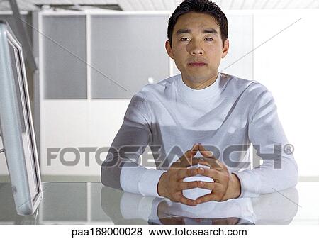 Stock Photo - Man sitting at desk, portrait. Fotosearch
