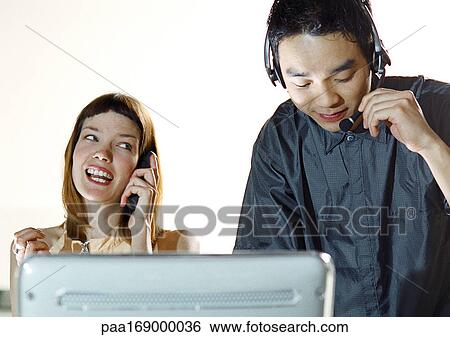 Man wearing headset, woman using cell phone View Large Photo Image Stock Photograph - Man wearing headset, woman using cell phone. Fotosearch