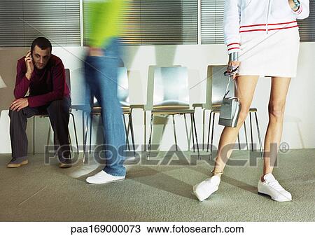 Stock Image - People in room with seats, low section, blurred motion. Fotosearch