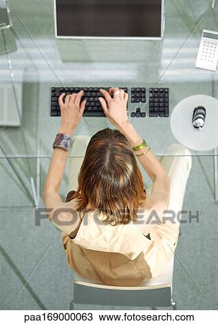 Woman at desk working on computer, elevated view View Large Photo Image Stock Image - Woman at desk working on computer, elevated view. Fotosearch