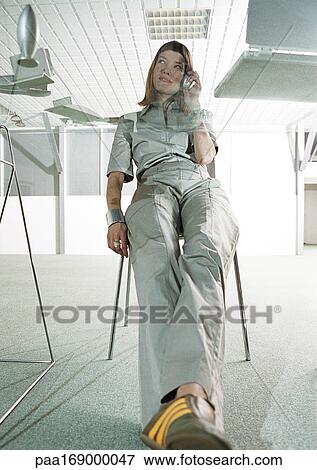 Stock Photo - Woman at glass desk using cell phone, low angle view. Fotosearch