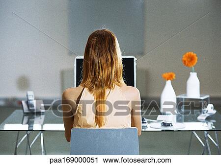 Woman sitting at desk, rear view View Large Photo Image Stock Image - Woman sitting at desk, rear view. Fotosearch