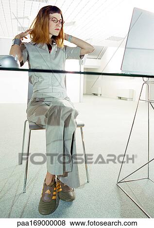 Woman sitting at desk, wearing tennis shoes View Large Photo Image Stock Photo - Woman sitting at desk, wearing tennis shoes. Fotosearch