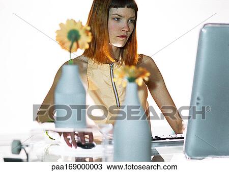 Stock Image - Woman using flat screen computer at desk. Fotosearch