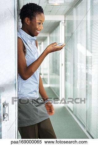 Woman with cell phone in hallway, smiling View Large Photo Image Stock Photography - Woman with cell phone in hallway, smiling. Fotosearch