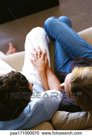 Couple sitting on sofa together, elevated view View Large Photo Image Stock Image - Couple sitting on sofa together, elevated view. Fotosearch