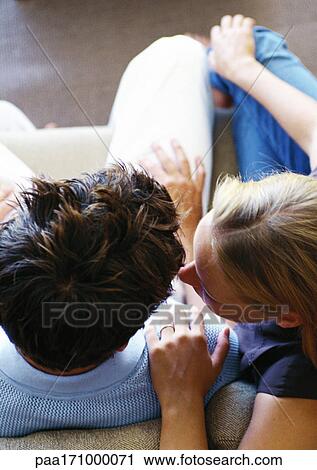 Couple sitting together on sofa, elevated vie View Large Photo Image Stock Image - Couple sitting together on sofa, elevated vie. Fotosearch