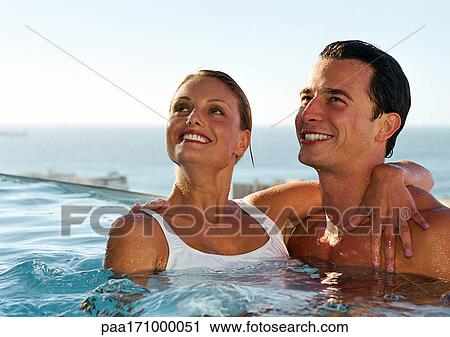 Stock Image - Couple together in swimming pool. Fotosearch