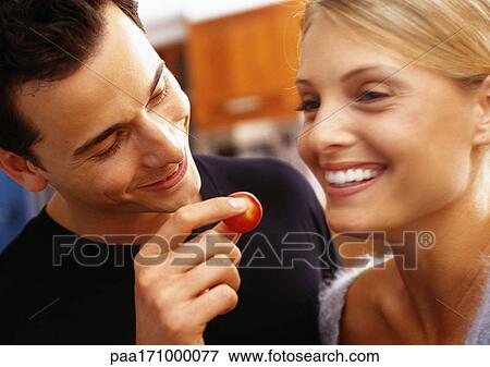 Man feeding woman cherry tomato with fingers, head and shoulders, close-up, blurred motion View Large Photo Image Stock Photo - Man feeding woman cherry tomato with fingers, head and shoulders, close-up, blurred motion. Fotosearch