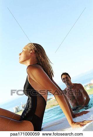 Man in swimming pool, woman sitting by edge of pool View Large Photo Image Stock Photo - Man in swimming pool, woman sitting by edge of pool. Fotosearch