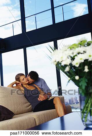 Stock Photograph - Man kissing woman's neck on sofa. Fotosearch