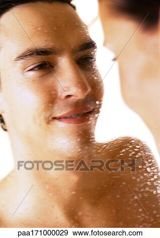 Stock Photo - Man looking at woman, man covered with droplets of water, close-up. Fotosearch