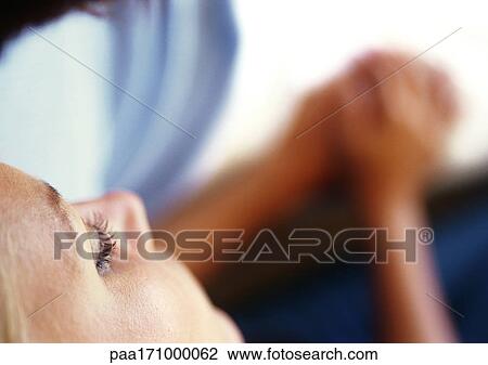 Stock Image - Woman's face, woman and man holding hands, blurred in background, high angle view. Fotosearch