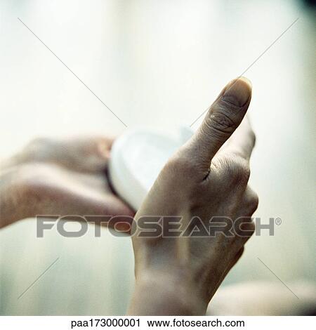 Stock Image - Hands holding beauty cream jar, close-up. Fotosearch