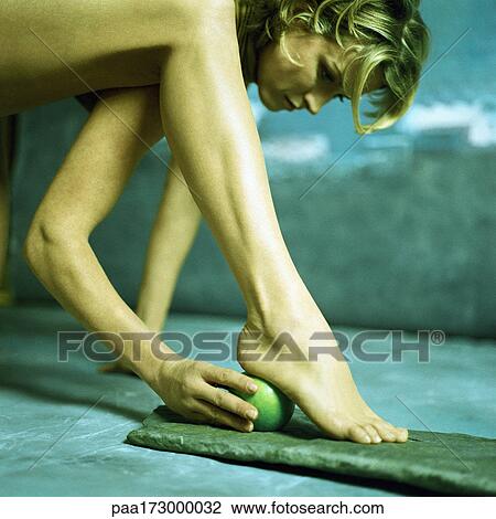 Stock Image - Woman holding apple under heel, low section. Fotosearch