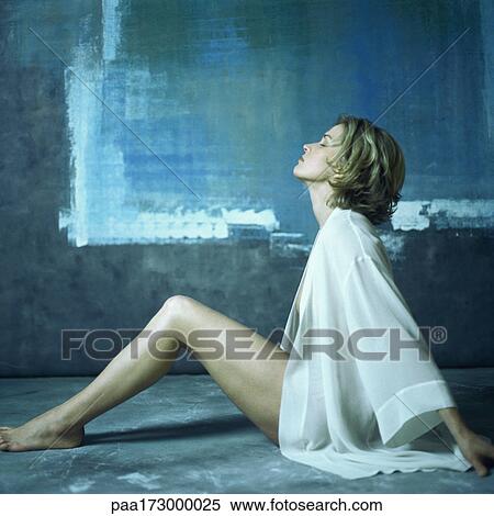 Stock Photography - Woman sitting with knees up, side view. Fotosearch