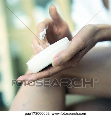 Woman's hand holding container of moisturizer, leg in background, close-up View Large Photo Image Stock Image - Woman's hand holding container of moisturizer, leg in background, close-up. Fotosearch