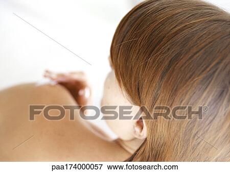 Stock Photo - Woman applying cream to elbow, rear view, blurred. Fotosearch