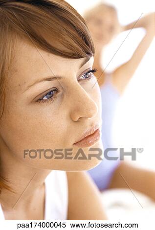 Woman looking away, second woman with hands behind head in background View Large Photo Image Stock Photography - Woman looking away, second woman with hands behind head in background. Fotosearch