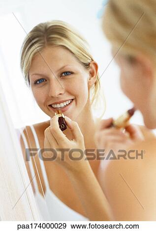 Woman putting on lipstick in mirror, portrait View Large Photo Image Stock Photo - Woman putting on lipstick in mirror, portrait. Fotosearch