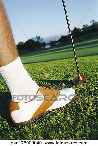 Stock Image - Golfer holding club, low section, close-up. Fotosearch
