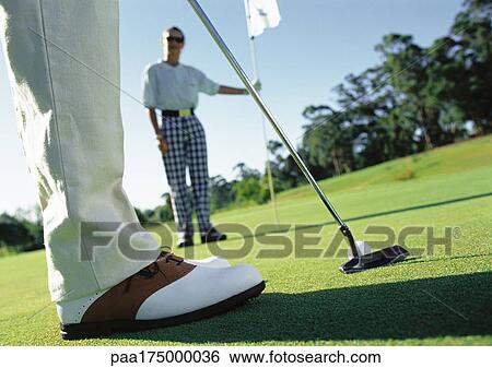 Golfer putting and second golfer holding pole View Large Photo Image Stock Photograph - Golfer putting and second golfer holding pole. Fotosearch
