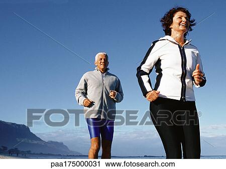 Mature couple running outdoors, low angle view View Large Photo Image Stock Image - Mature couple running outdoors, low angle view. Fotosearch