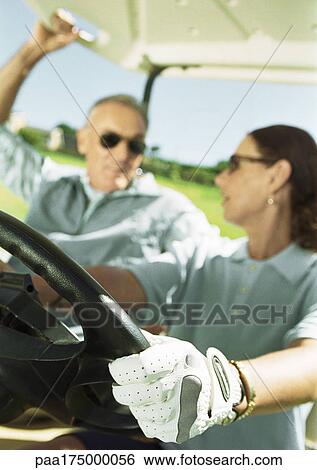 Mature man and woman in golf cart, close-up, focus on hand and steering wheel in foreground View Large Photo Image Stock Photograph - Mature man and woman in golf cart, close-up, focus on hand and steering wheel in foreground. Fotosearch